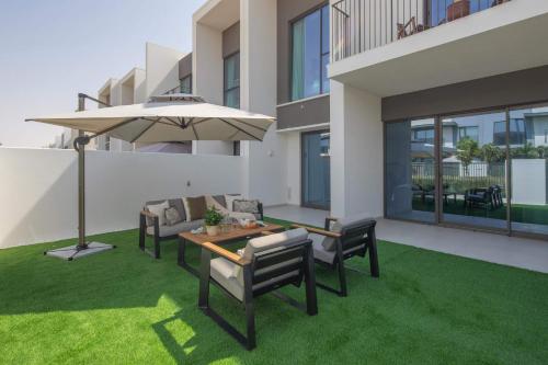 a patio with a table and chairs and an umbrella at Frank Porter - Nara, The Valley in Dubai