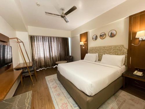 a bedroom with a large white bed and a television at Comfort Hotel Vista in Lucknow
