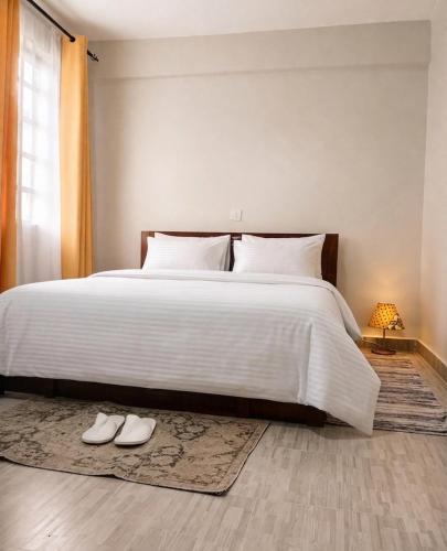 a bedroom with a large white bed and a pair of shoes at Esidai Sidai in Narok