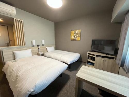 a hotel room with two beds and a flat screen tv at Hotel Route Inn Imabari in Imabari