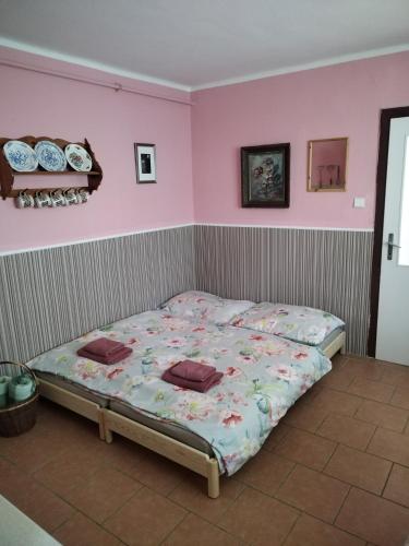 a bed in a room with a pink wall at Ubytování U Trati in Moravská Nová Ves
