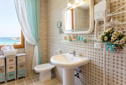 a bathroom with a sink and a toilet and a mirror at ClickSardegna Villa Emanuel spectacular sea view, with independent swimming pool in Alghero