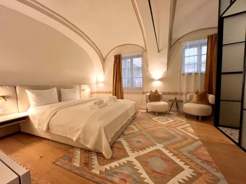 a bedroom with a large white bed and a room with windows at Muresenilor 9 Boutique - Old Town in Braşov
