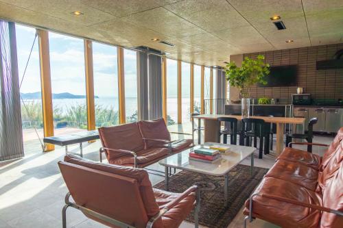 a living room with chairs and tables and a kitchen at KAMOME SLOW HOTEL in Awaji