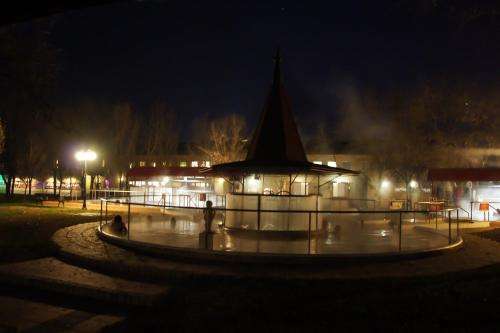 a fountain in a park at night with a building at Solaris Apartman&Resort in Cserkeszőlő