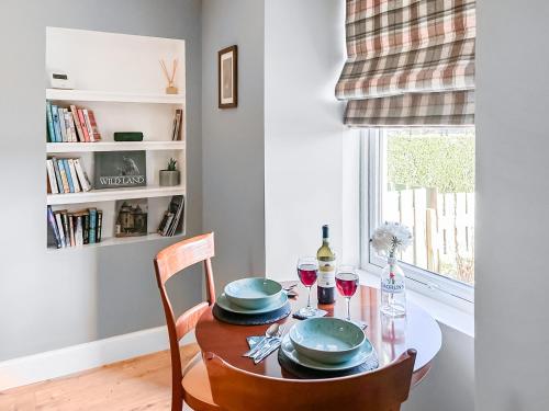 a dining room table with two chairs and wine glasses at Rose Cottage in Freuchie