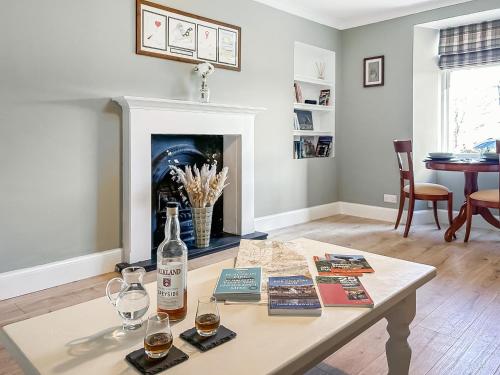 a living room with a table with a bottle of wine at Rose Cottage in Freuchie