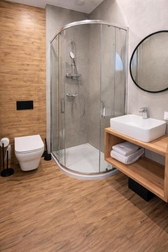 a bathroom with a shower and a sink and a toilet at New Corner Apartamenty in Niechorze