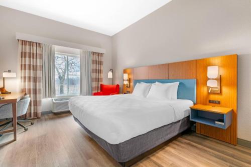 a hotel room with a large bed and a desk at Country Inn & Suites by Radisson, West Bend, WI in West Bend