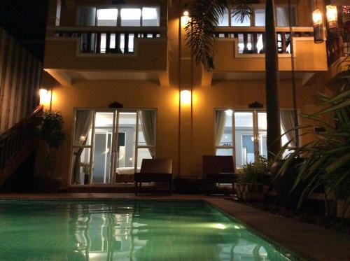 a swimming pool in front of a building at night at Ramchang Guesthouse in Battambang