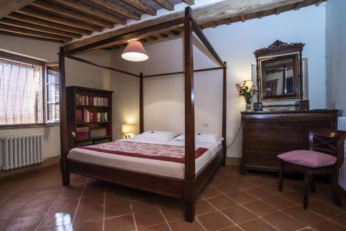 Schlafzimmer mit Himmelbett und Spiegel in der Unterkunft Fattoria Le Pietre Vive di Montaperti in Montaperti