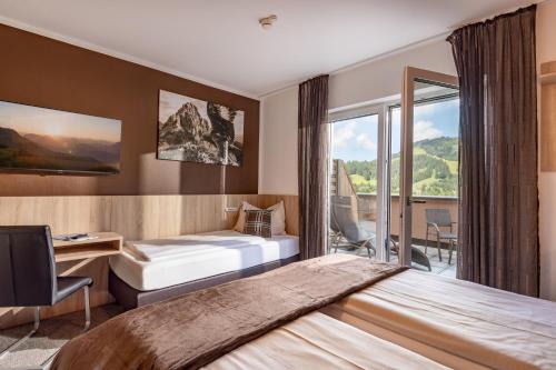 a hotel room with a bed and a desk and window at Fairhotel Hochfilzen B&B in Hochfilzen
