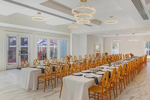a banquet hall with tables and chairs and a chandelier at The Colonial Inn, an Ascend Collection Hotel in Hillsborough