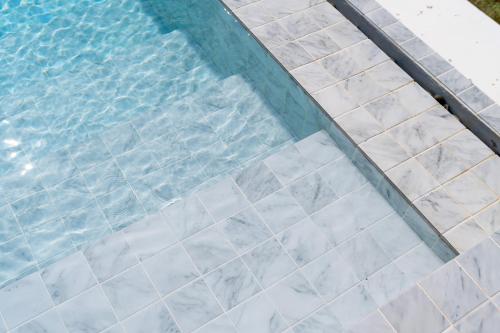 a swimming pool with a tile floor and water at Grood Glamping in Ban Khok Sung