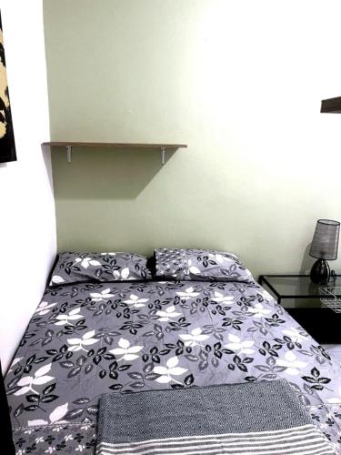 a bed with a black and white comforter in a bedroom at Cocon lumineux tout équipé in Dzaoudzi