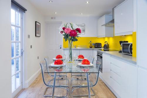 a kitchen with a glass table with a vase of flowers at Charming Tower Bridge Apartment in London