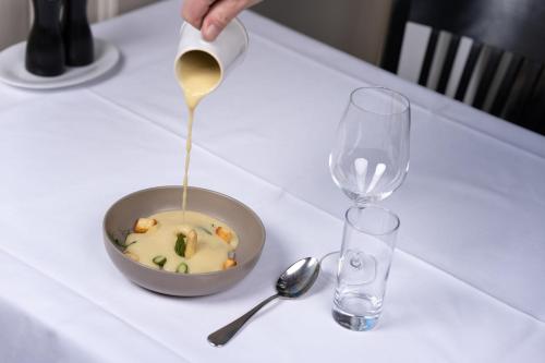 a person pouring gravy into a bowl of soup next to a glass at Hotel Zofingen in Zofingen
