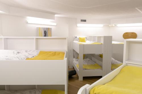 ein Zimmer mit weißen Etagenbetten und gelben Betten in der Unterkunft Hostel LR in Nazarje