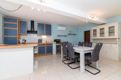 a kitchen with blue cabinets and a white table and chairs at House Nešpula in Veli Lošinj