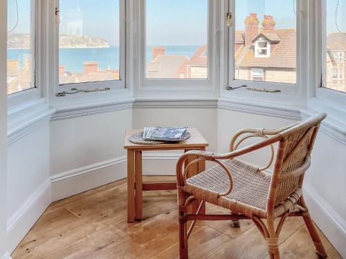 a chair and a table in a room with windows at Flat 4 Sea Court in Swanage