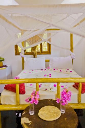 a bedroom with a bed with flowers on a table at Mbao Boutique Bungalows in Jambiani
