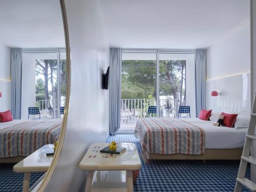 ein Hotelzimmer mit zwei Betten und einem Spiegel in der Unterkunft Amadria Park Kids Hotel Andrija in Šibenik
