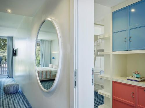 ein Badezimmer mit Spiegel und ein Schlafzimmer mit Bett in der Unterkunft Amadria Park Kids Hotel Andrija in Šibenik