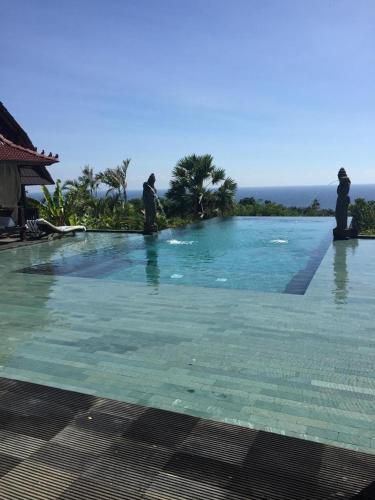 a swimming pool with statues in the water at Singa Villas in Ungasan