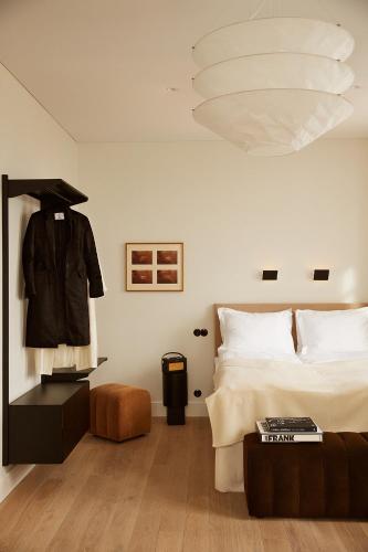 Ein Schlafzimmer mit einem Bett und einer schwarzen Jacke an einem Kleiderständer in der Unterkunft Mjólk Hotel in Reykjavík