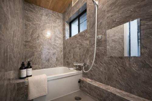 a bathroom with a tub and a sink and a mirror at Shinimamiya Ebisu 戎 in Osaka