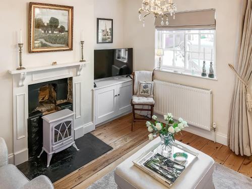 a living room with a fireplace and a tv at Bay Cottage in Ripon
