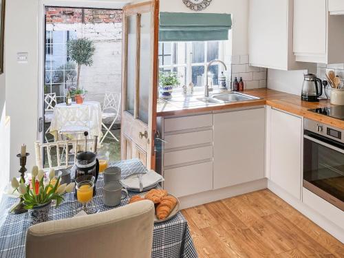 a kitchen with white cabinets and a table with food on it at Bay Cottage in Ripon