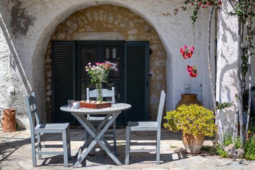 a table with two chairs and a table with flowers on it at Green Blue Kardamyli in Kardamyli