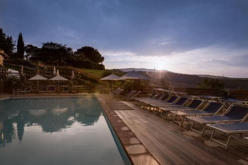 a swimming pool with lounge chairs and the sun setting at Borgo Il Poggiaccio Residenza d'Epoca in Sovicille
