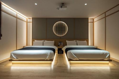 a bedroom with two beds and a mirror at Anook Ryokan Hotel Daejeon Yuseong in Daejeon