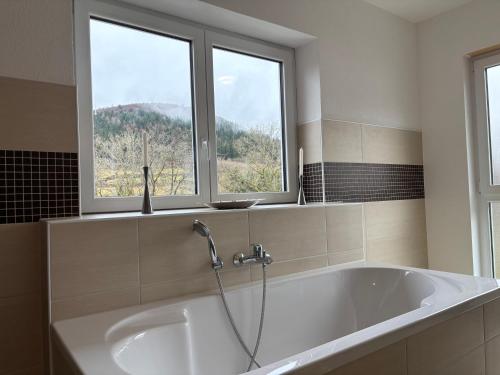 a bath tub in a bathroom with two windows at Entspannung am Wald in Wald-Michelbach