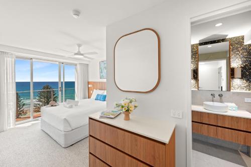 a bathroom with a sink and a mirror and a bed at Pacific Regis Beachfront Holiday Apartments in Gold Coast