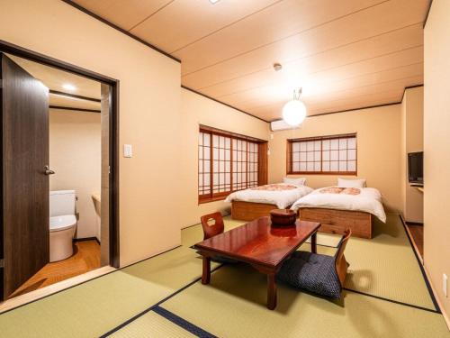 a room with two beds and a table in it at Hakoneyumoto Yamatokan 箱根湯本 温泉旅館 大和館 in Hakone