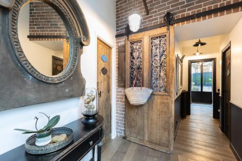 a hallway with a mirror and a brick wall at Villa cosy Paris in La Garenne-Colombes