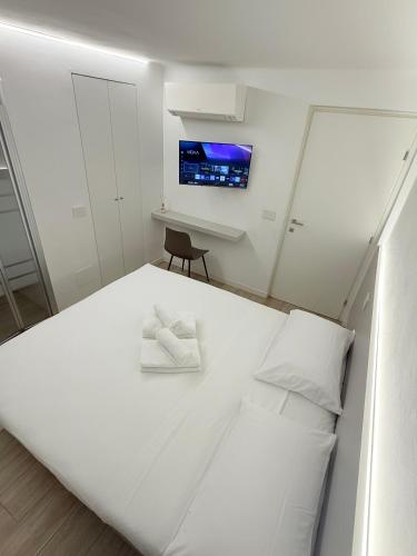 a bedroom with a white bed with a tv on the wall at Colombo 365 in Civitanova Marche