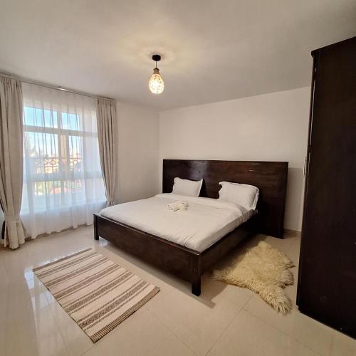 a bedroom with a bed and a window and a rug at Zerani Homes in Ruaka