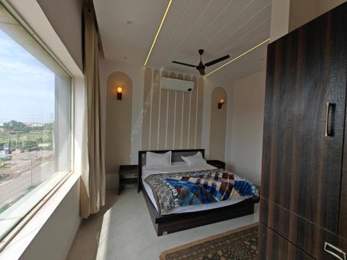 a bedroom with a bed and a large window at Hotel Plain A Quiet Stay in Mubārikpur