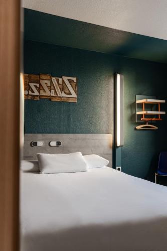 a bedroom with a white bed and a green wall at Ibis Budget Le Havre Les Docks in Le Havre