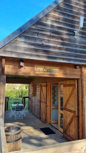 a wooden building with doors and a table and a barrel at Les Chalets de la Besbre in Jaligny