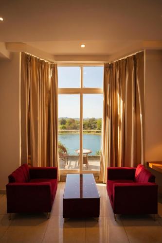 a living room with two red couches and a large window at Hotel JMS Grand in Jaunpur