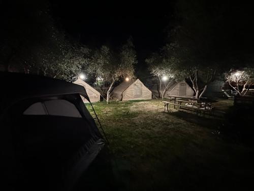 a field with a picnic table and tents at night at Garden Lake Camping in Ksamil
