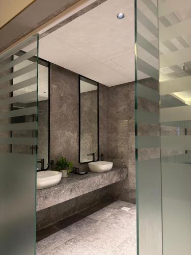 a bathroom with two sinks and two mirrors at Roxy Hotel & Apartment Lawas in Lawas