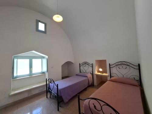 a bedroom with two beds and a window at Le Villette Li Sarruni by SalentoInVacanzaCOM in Lido Marini