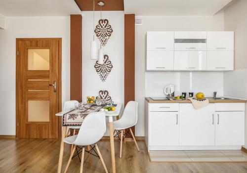 a kitchen with white cabinets and a table with white chairs at U Lampy in Zakopane