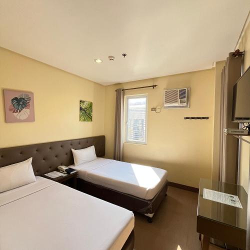 a hotel room with two beds and a window at Hotel 801 in Cagayan de Oro